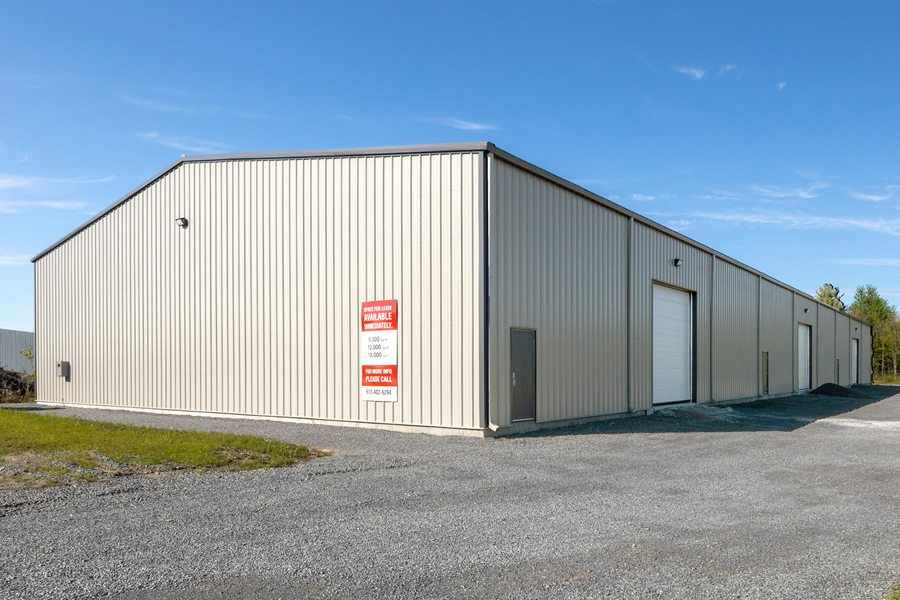 Multi-unit metal flex building with overhead doors and a space-for-lease sign